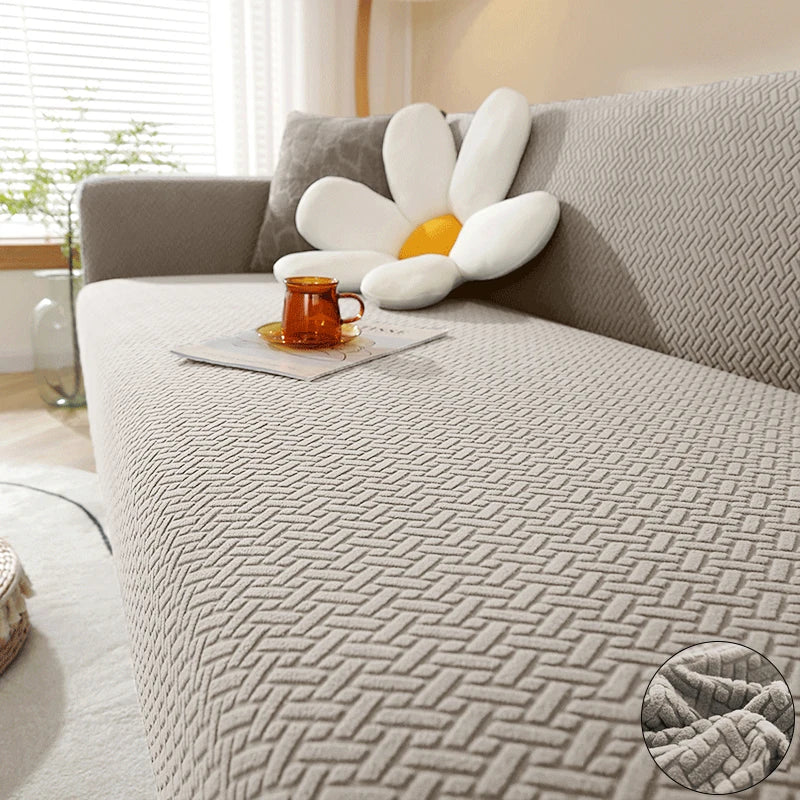 A light gray jacquard sofa cover featuring a decorative white and yellow flower accent cushion.