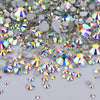 A close-up view of a mix of clear glass rhinestones and silver sequins scattered on a white surface.