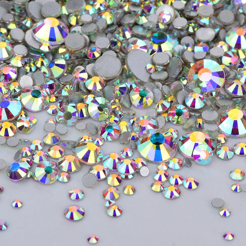 A close-up view of a mix of clear glass rhinestones and silver sequins scattered on a white surface.