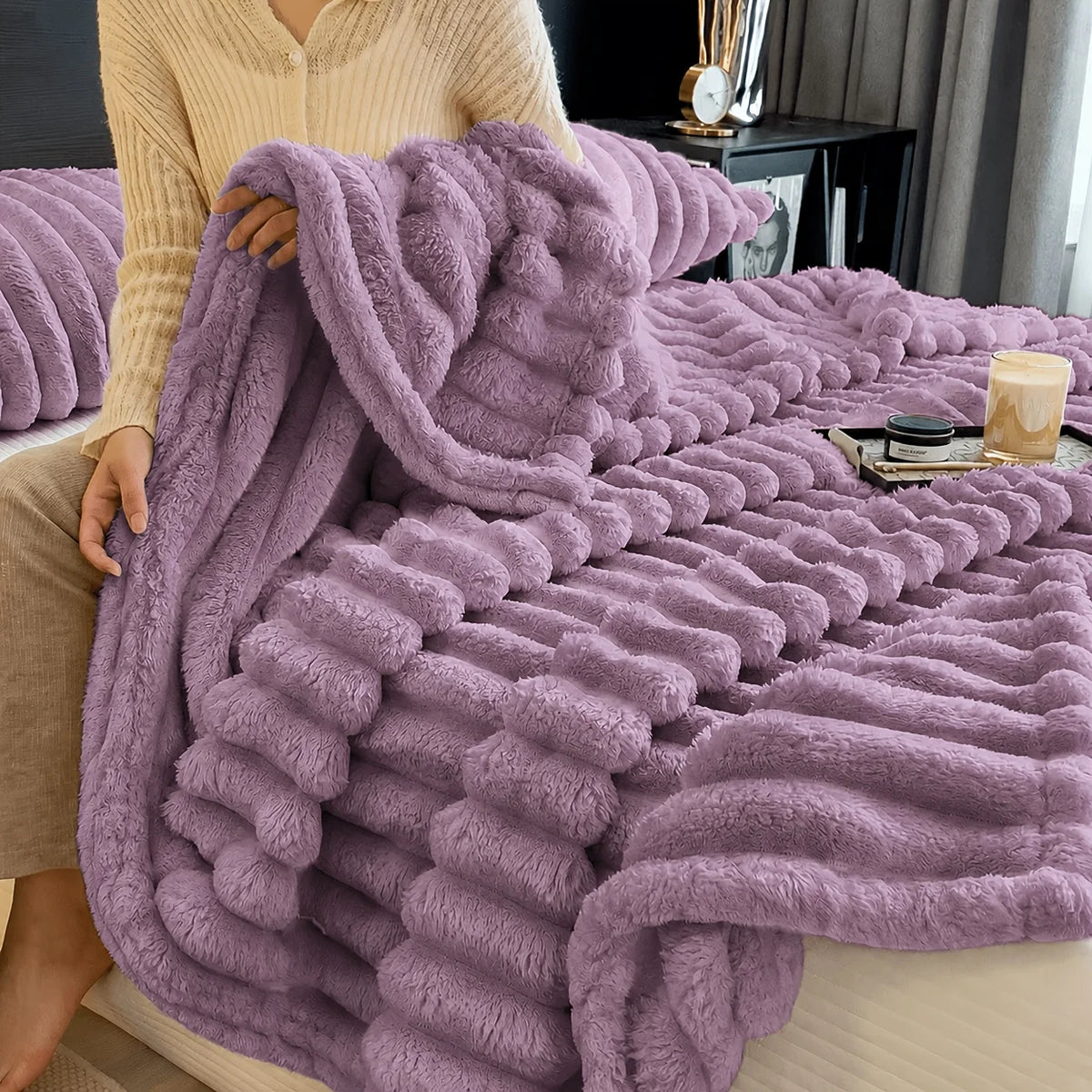 A fluffy purple fleece throw blanket draped over a person's lap.
