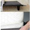 A hand is folding a gray box spring protector cover over a white pillow.