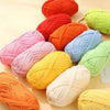 A collection of thick polyester craft yarn in various shades including orange, pink, yellow, and green, displayed on a light 