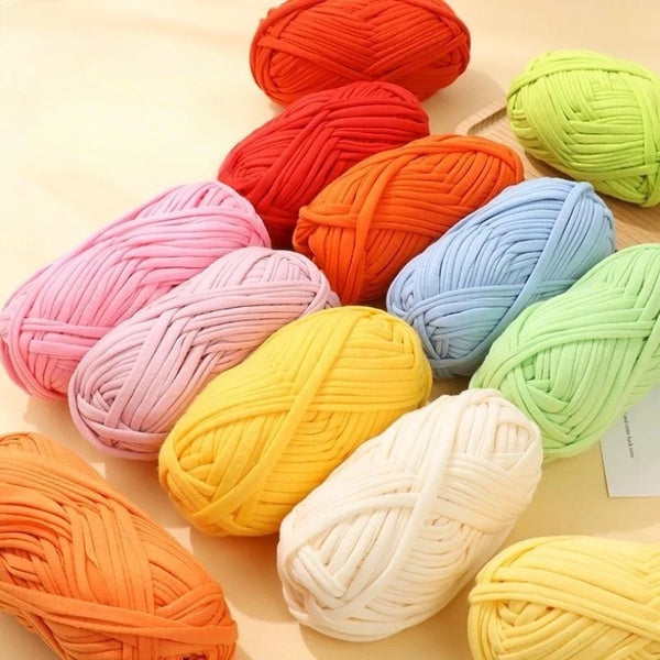 A collection of thick polyester craft yarn in various shades including orange, pink, yellow, and green, displayed on a light 
