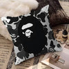 A decorative pillow cover featuring a black and white camouflage print with a stylized face design.