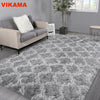 A fluffy gray geometric plush area rug placed on a wooden floor in a modern living room setting.