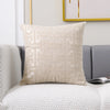 A beige geometric jacquard lumbar pillow cover resting on a gray sofa and white textured fabric.