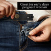 A hand is shown adjusting an adjustable elastic waist extender belt on a pair of blue jeans.