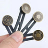 A hand holds a black universal waist extender button for jeans and pants with brass accents.