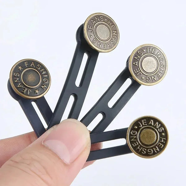 A hand holds a black universal waist extender button for jeans and pants with brass accents.