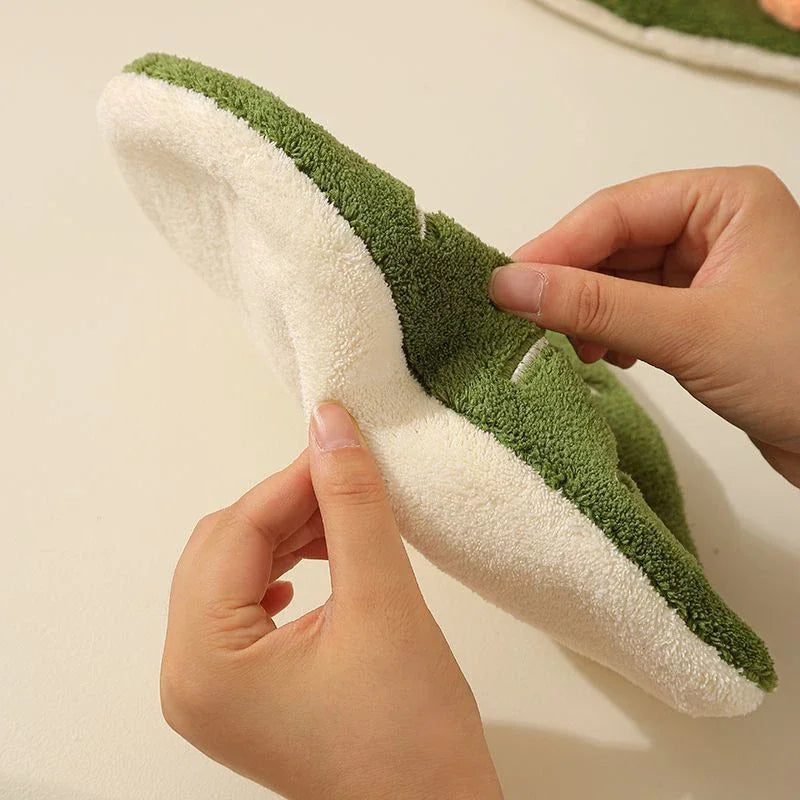 A hand is holding a white and green embroidered leaf hand towel.