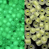 A close-up view of small, translucent green glow-in-the-dark glass seed beads.