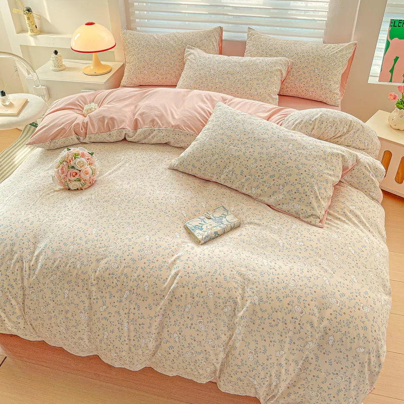 A floral printed bedding set featuring pink and cream tones on a bed with light wood flooring.