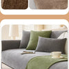 A sofa is covered with a gray fabric and accented by olive green pillows and a matching throw.