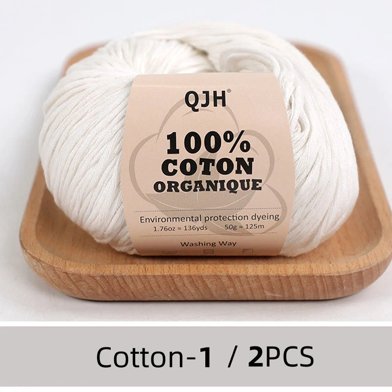 A ball of natural cream colored 100% organic cotton yarn labeled QJH for knitting and crochet