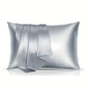 A silver satin pillowcase is folded and displayed on a white surface.