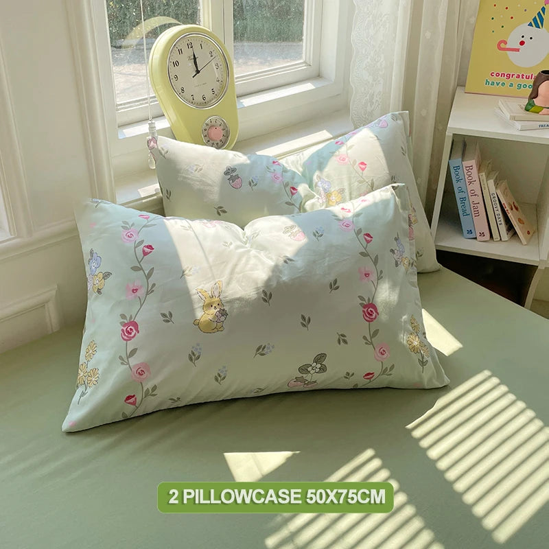 A set of two light blue and white floral pillowcases displayed on a green surface.
