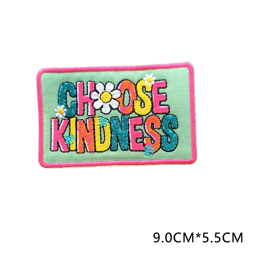 A pink embroidered patch with green lettering that reads Choose Kindness and features small yellow flowers.