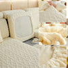 Close-up view of a cream colored plush velvet sofa cover with a quilted texture and anti-slip backing.