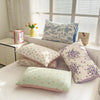 A collection of floral printed pillow covers in shades of blue, purple, and pink displayed on a white surface.