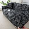 A stretchable festive sofa cover with a black and gray skull pattern displayed on a sofa.