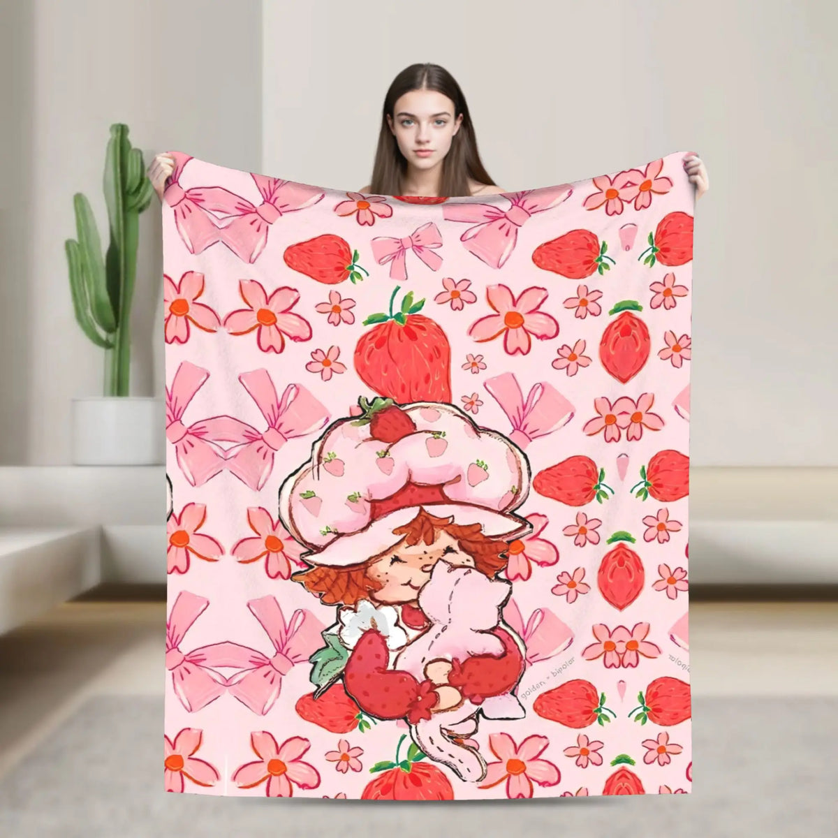 A pink strawberry shortcake plush throw blanket featuring a pattern of strawberries and flowers.