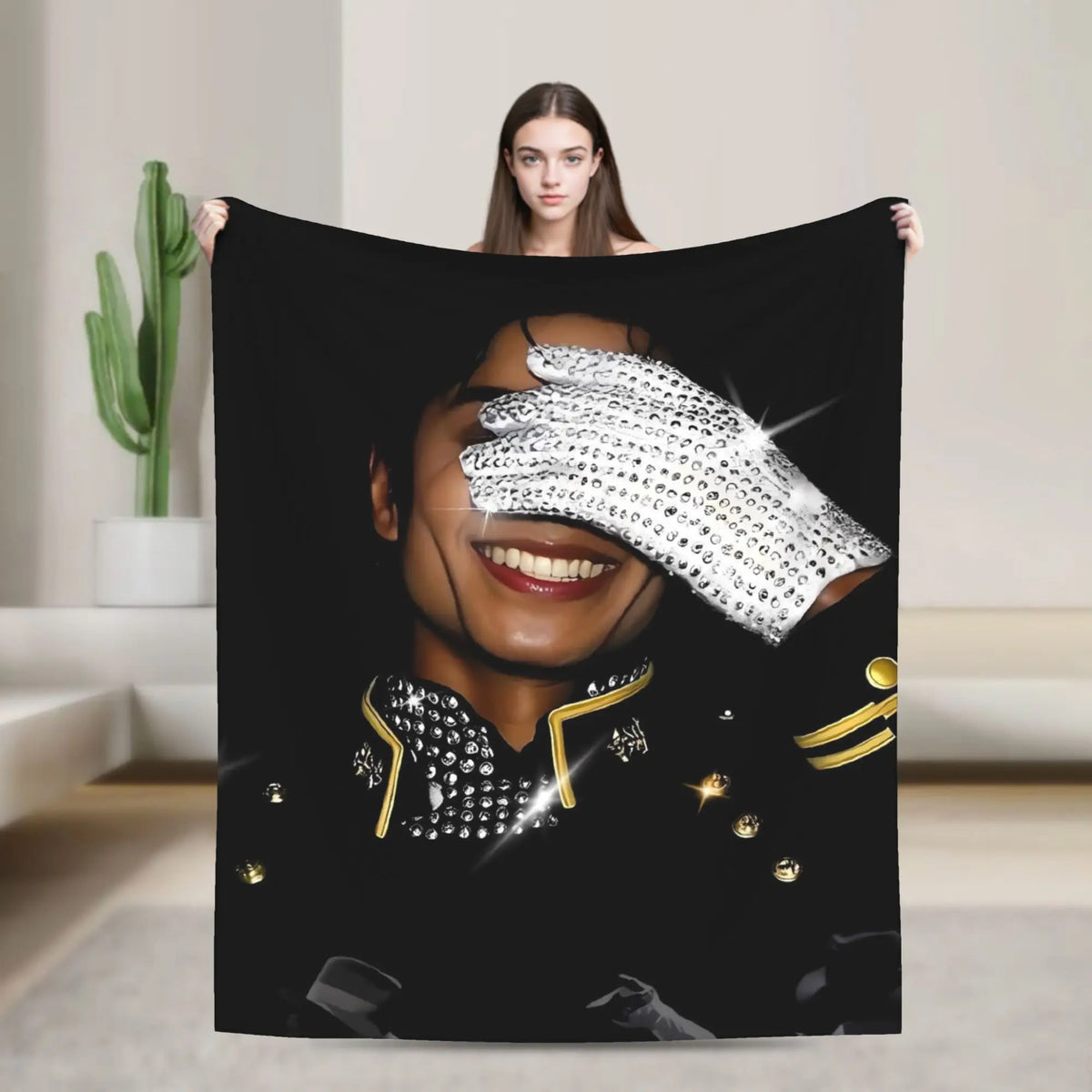 A woman holds up a black graphic plush throw blanket featuring a close-up portrait of a smiling face with sparkling details.