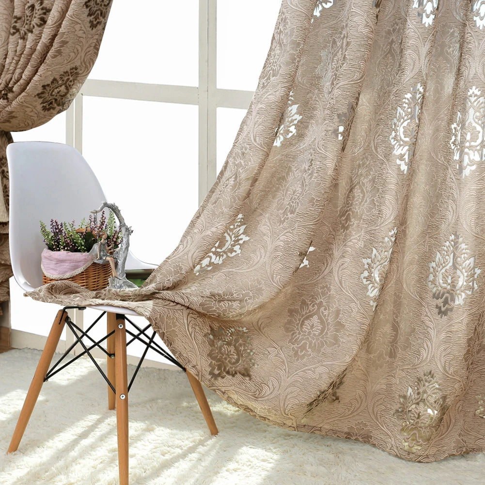 A sheer beige jacquard curtain panel draped over a white chair near a window.