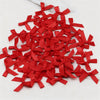 A pile of small red satin ribbon bows scattered on a white marble surface.
