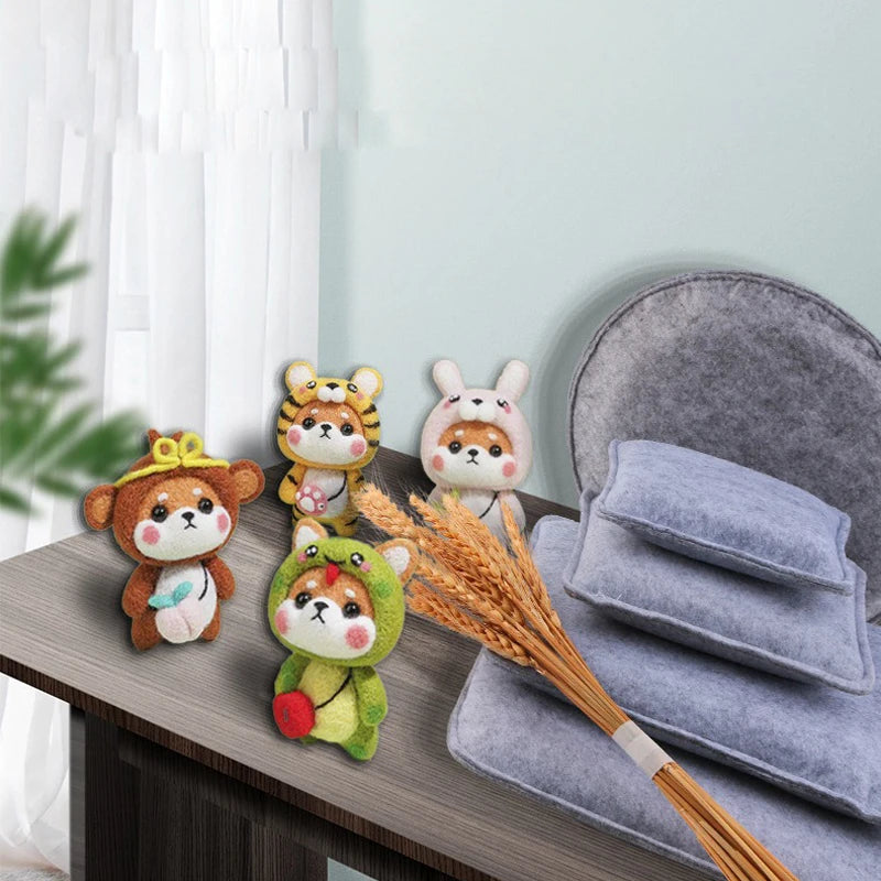 A collection of multi-size needle felting animal figures in various colors and textures displayed on a wooden surface.