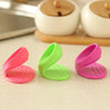 Three silicone oven mitts in pink and green colors are displayed on a light surface.
