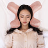 A woman is lying down with a pink satin anti-wrinkle pillow shaped like bunny ears around her head.