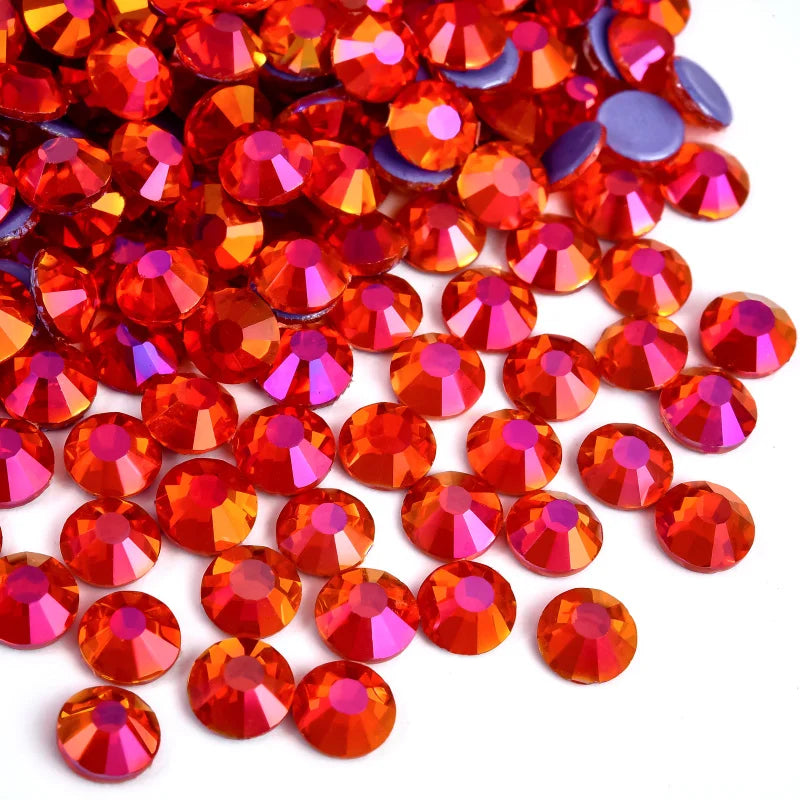 A pile of flatback glass rhinestones in various shades of orange, red, and purple.
