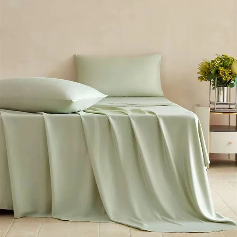 A light sage green bamboo fiber flat bed sheet draped over a bed with white pillows.
