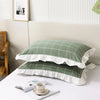 A set of two soft plaid washed cotton pillowcases with ruffled edges displayed on a white surface.