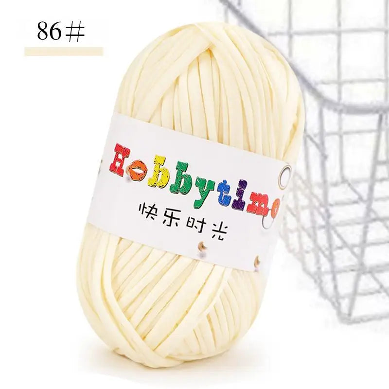 A ball of thick, cream-colored polyester craft yarn is shown against a wire mesh background.