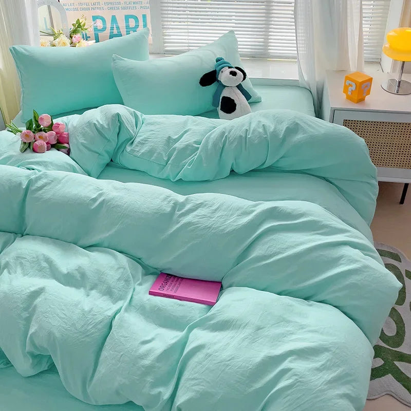 A light aqua cotton bed linen set featuring a teal duvet, pillows, and a stuffed animal decoration.