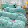 A light aqua cotton bed linen set featuring a teal duvet, pillows, and a stuffed animal decoration.