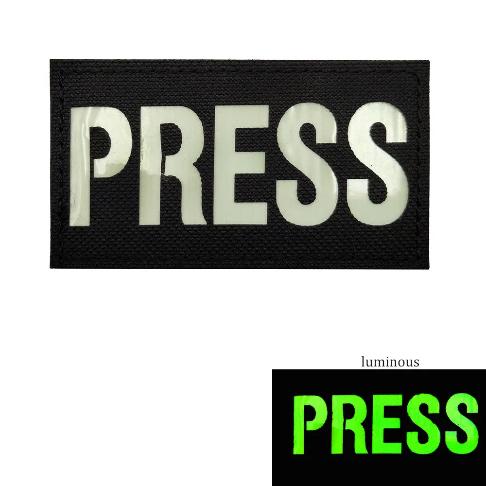 Black press embroidered patch with white text on a black background