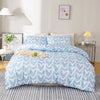 A light blue duvet cover set with a white heart print displayed on a bed in a bright room.