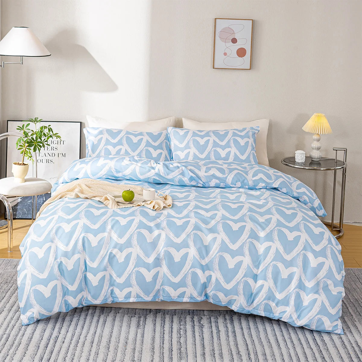 A light blue duvet cover set with a white heart print displayed on a bed in a bright room.