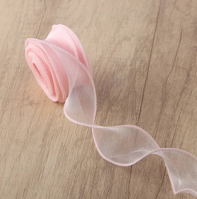 Pink organza ribbon rolled and unwound on a wooden surface