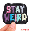 A black embroidery patch with the text STAY WEIRD stitched in various bright colors like pink purple and blue.