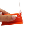 A hand holds an orange automatic double-head sewing needle threader with a thin metal needle.