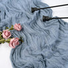 A soft blue-gray gauzy fabric draped with pink roses and black decorative tools.