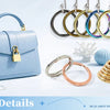 A collection of round metal rings and fabric-covered shank buttons displayed next to a light blue leather handbag.