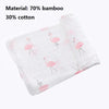 A white muslin swaddle blanket featuring pink flamingo embroidery, made from a bamboo and cotton blend.