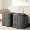 Two gray fabric storage bags standing next to a sofa in a bright living room.