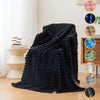 A dark black fluffy flannel throw blanket draped on a light-colored surface with color swatches.