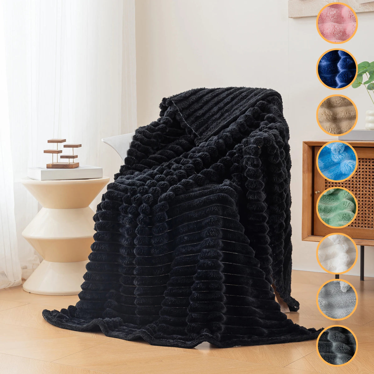 A dark black fluffy flannel throw blanket draped on a light-colored surface with color swatches.