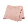 A folded pink knit baby blanket with small eyelet details.